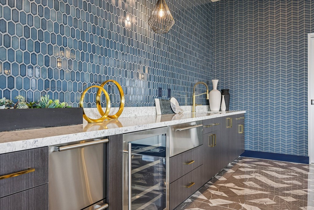 A kitchen with a marble counter top and a wall covered in hexagonal tiles.