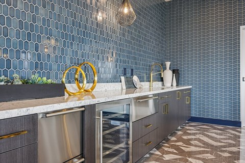 A kitchen with a marble counter top and a wall covered in hexagonal tiles.