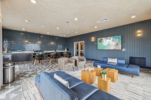 A modern living room with a blue couch and a television on the wall.