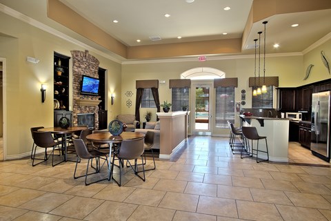 A spacious living room with a stone fireplace and a dining table set up.