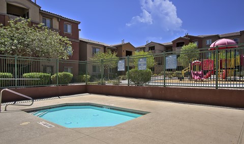 A small pool in a fenced in area with a slide.