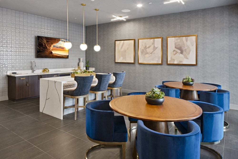 a dining room with blue chairs and tables and a kitchen at Aura Vegas Apartments, Las Vegas, NV 89103