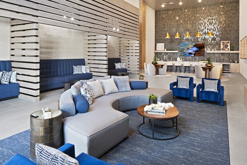 a lobby with blue chairs and couches and a coffee table at Aura Vegas Apartments, Las Vegas, NV