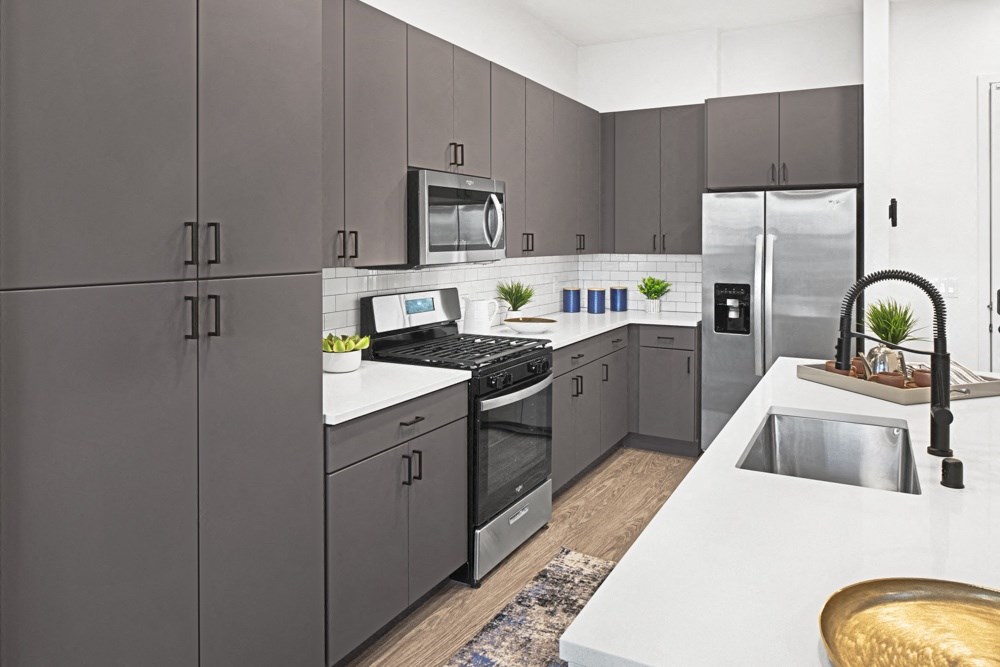 a modern kitchen with stainless steel appliances and white counter tops a modern kitchen with stainless steel appliances and white counter tops at Aura Vegas Apartments, Las Vegas, NV 89103