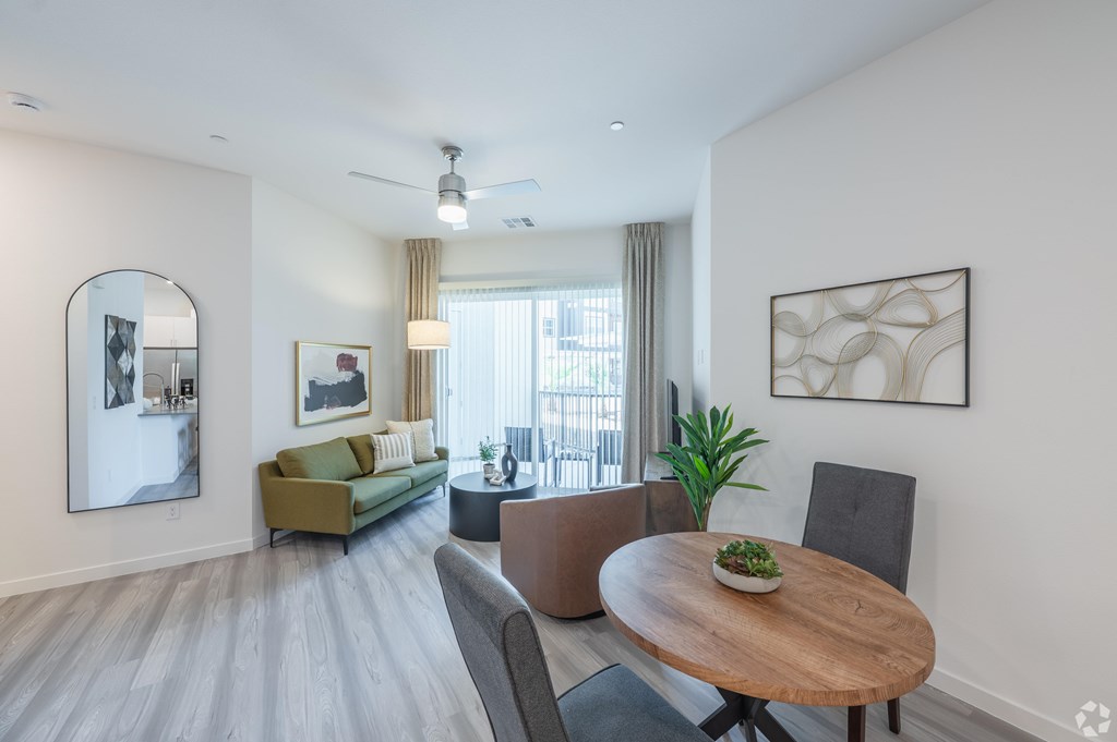 A modern living room with a wooden table and grey chairs.