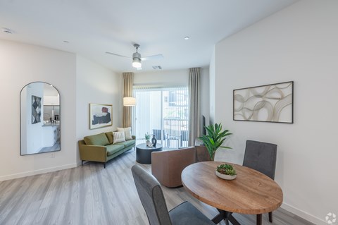 A modern living room with a wooden table and grey chairs.
