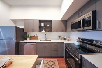 a kitchen with gray cabinets and a wooden table at Hana Apartments, Hillsboro, Oregon