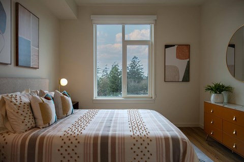 Bedroom with patterned bedding and round mirror at Montage Apartments, Tigard, OR