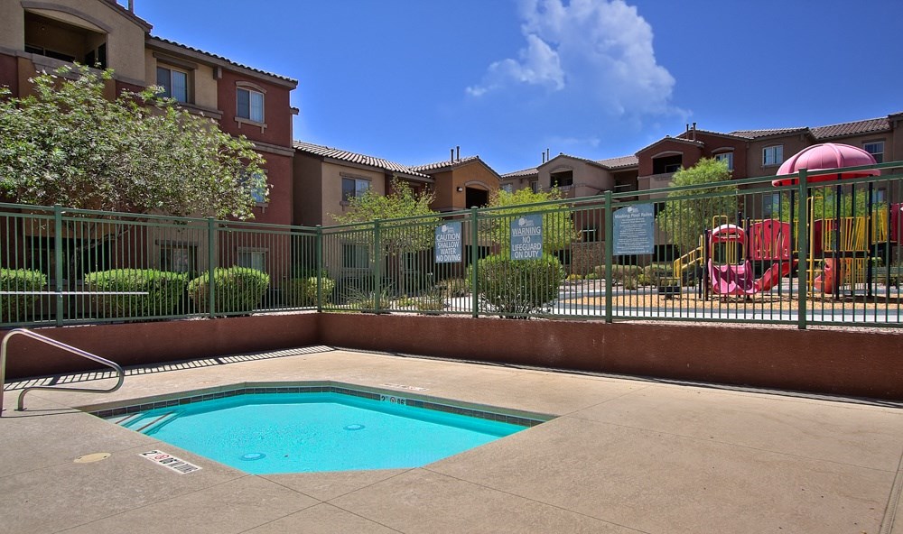 a swimming pool with a playground and buildings in the background
