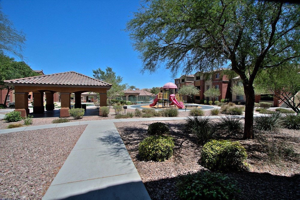 a park with a playground and a gazebo in front of a building