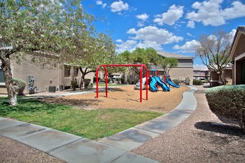 A playground with a red swing set and a blue slide.