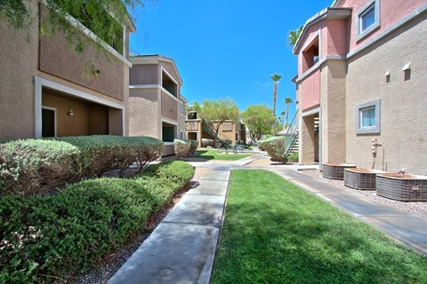 A sunny day in a residential area with apartment buildings and a sidewalk.