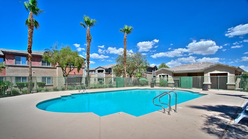 a swimming pool with palm trees and buildings in the background