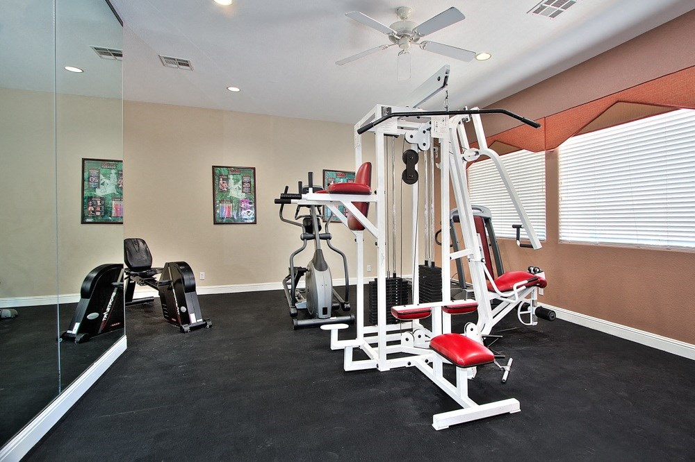 a home gym with exercise equipment and a ceiling fan