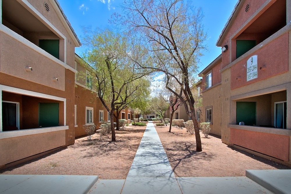 a courtyard between two buildings with trees and a sidewalk