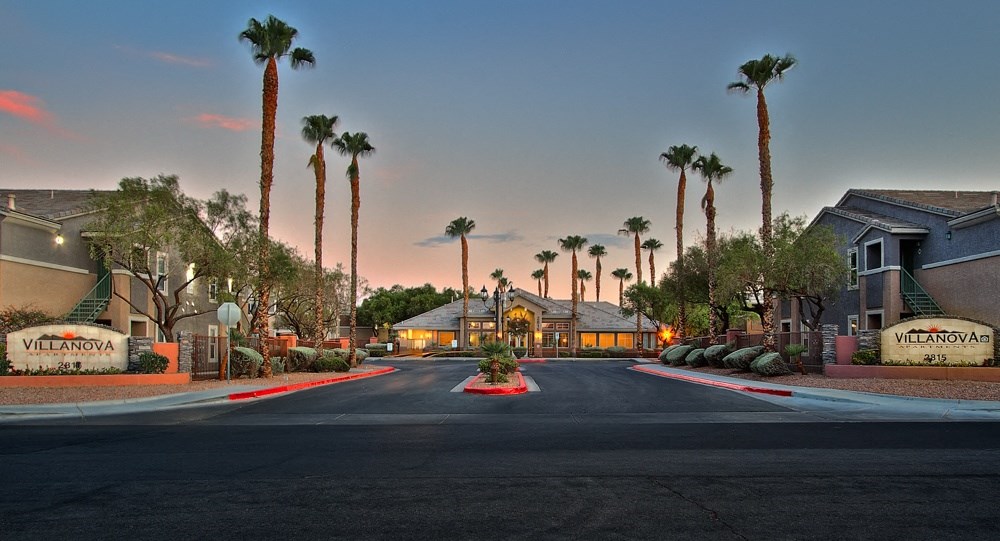 a street with houses and palm trees at sunset