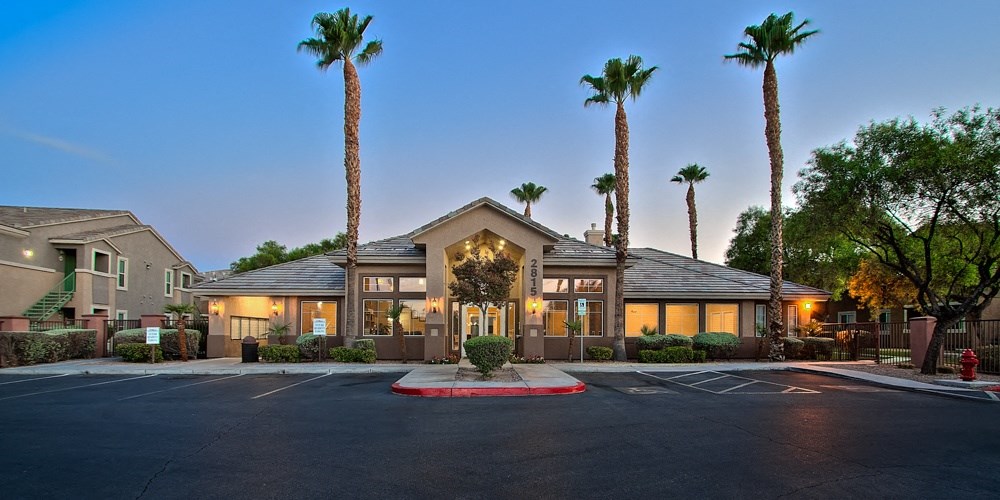 a building with palm trees in front of it and a parking lot