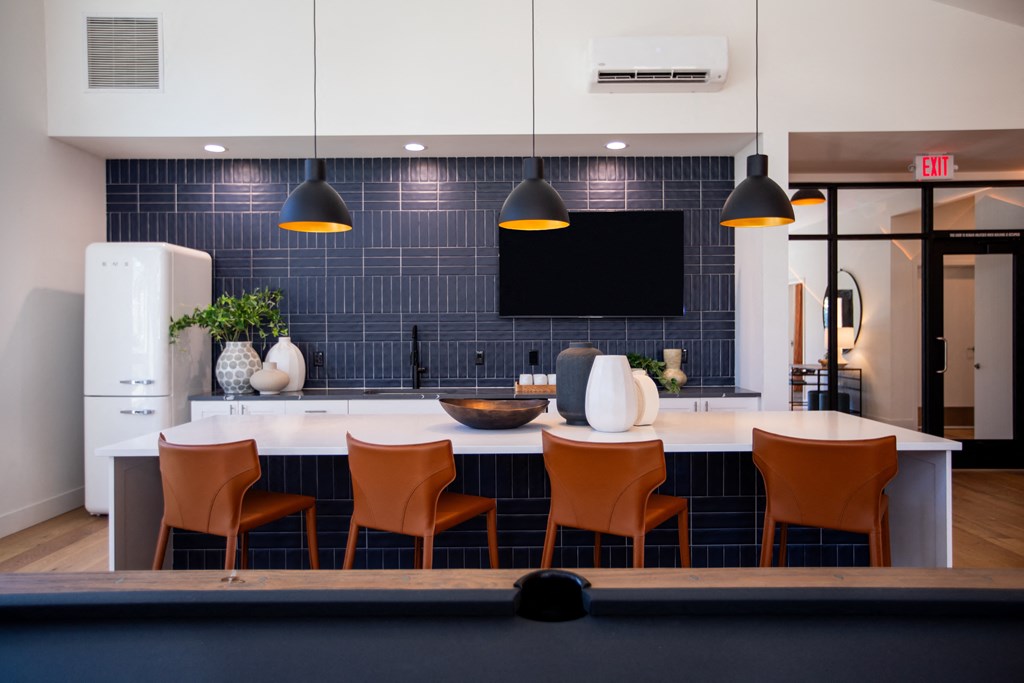 a kitchen with a counter and chairs in front of a blue tile wall