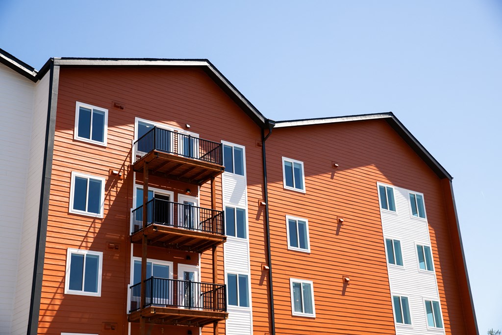a large building with balconies and a blue sky at The Mill on Maple Apartments, Oregon