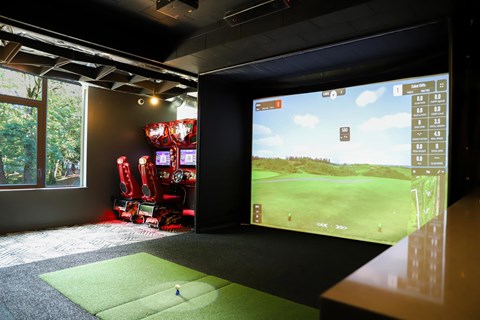 A golf simulator room with a screen showing a golf course.