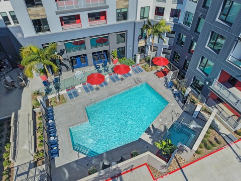 A swimming pool surrounded by red umbrellas and blue chairs.