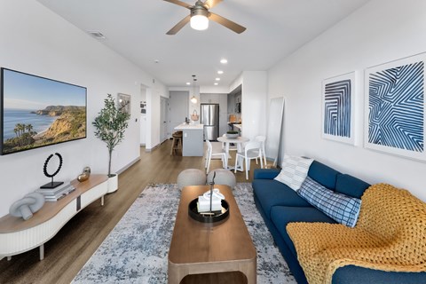 A living room with a blue couch and a painting on the wall.