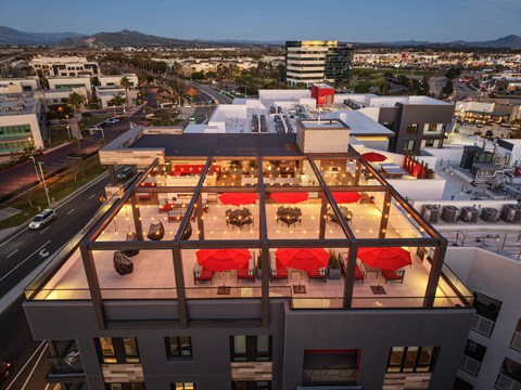 A rooftop restaurant with red umbrellas and tables.