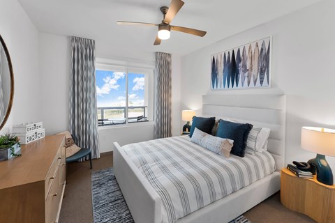 A bedroom with a large bed, a desk, and a ceiling fan.