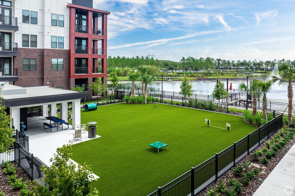 A view of a green lawn with a table and chairs in front of a building.