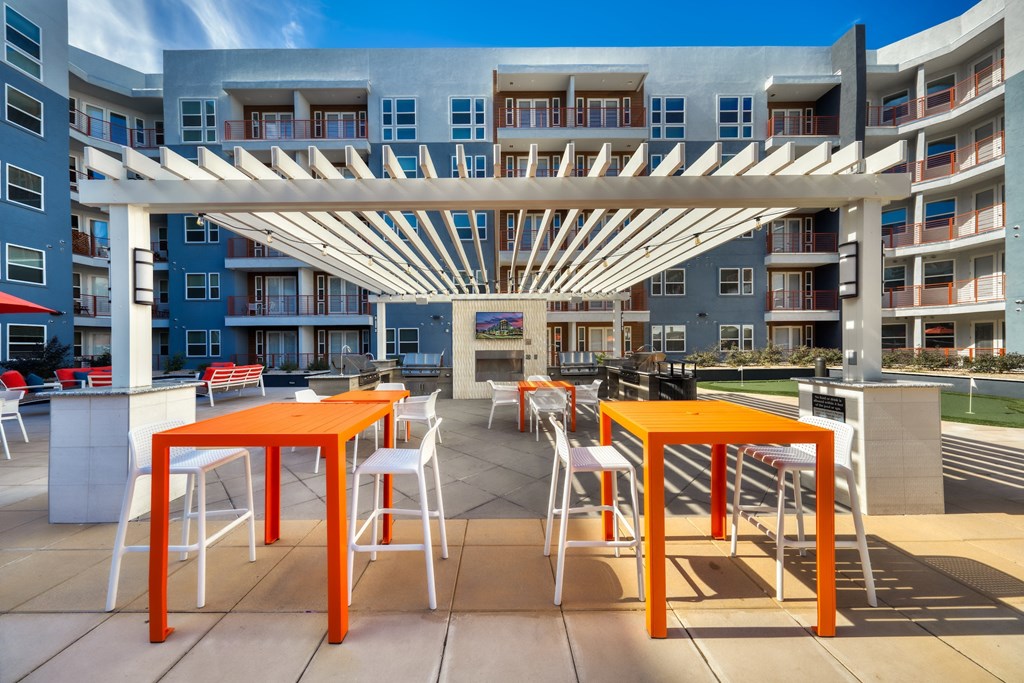 an outdoor patio with orange tables and white stools at The Rey Downtown, Arizona