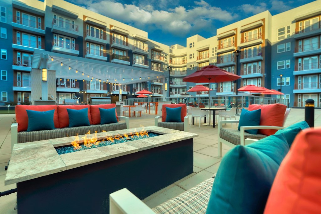 a seating area with couches and tables with umbrellas and a fire pit at The Rey Downtown, Arizona