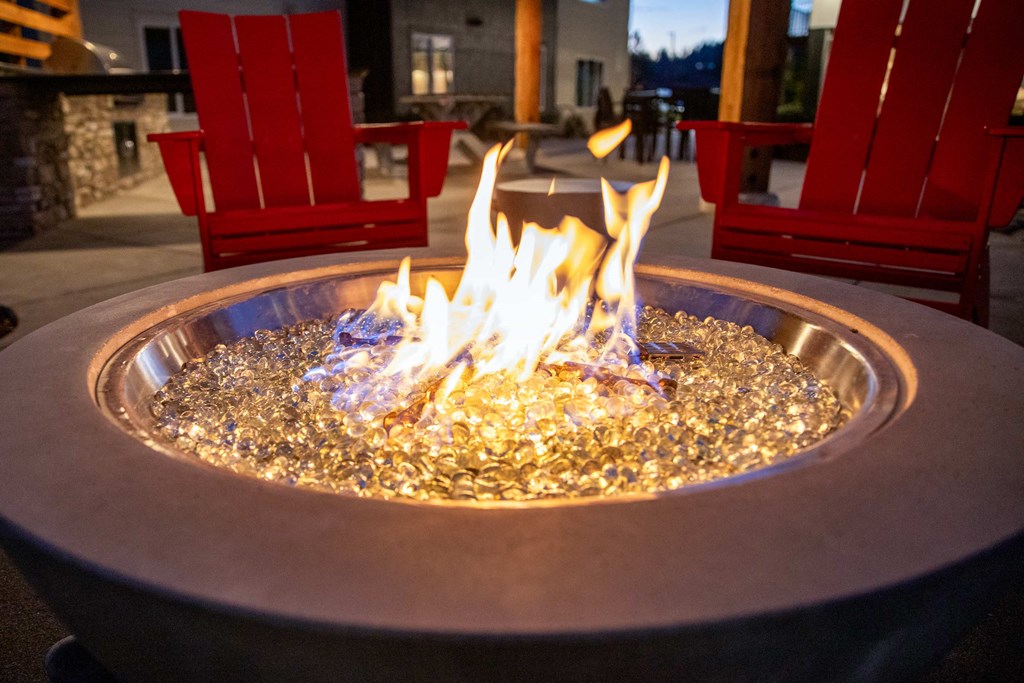 a fire pit in the middle of a patio with red chairsat Scouter's Mountain, Happy Valley Oregon