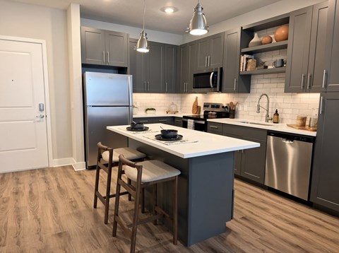 A kitchen with a white countertop and a stainless steel refrigerator.