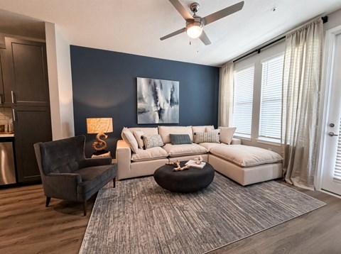 A modern living room with a grey rug, a black chair, a white sofa, and a painting on the wall.