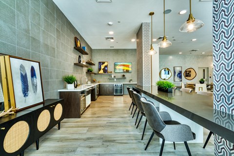 a communal area with a long counter and chairs in a room with a kitchen