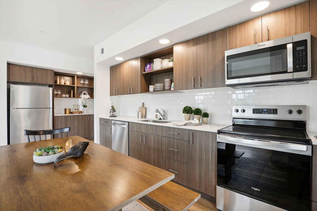 a kitchen with stainless steel appliances and a wooden table at The Mill on Maple Apartments, Oregon City