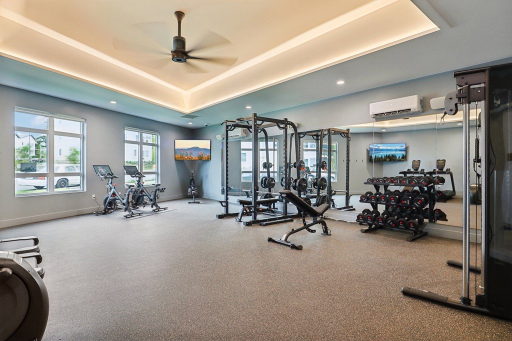 a gym with weights and other exercise equipment on the floor and windows at The Mill on Maple Apartments, Oregon City