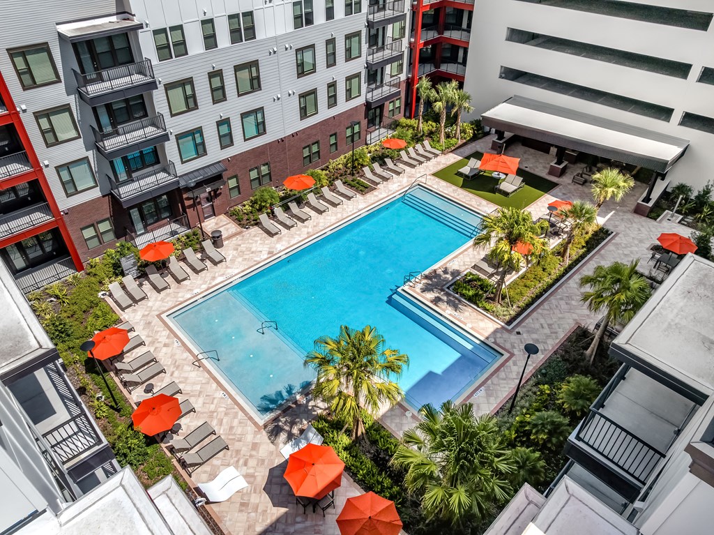 A swimming pool surrounded by red umbrellas and lounge chairs.