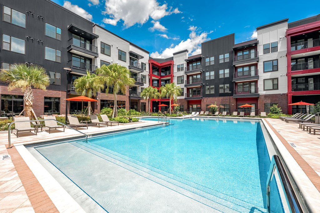 A large swimming pool in front of a multi-story apartment building.