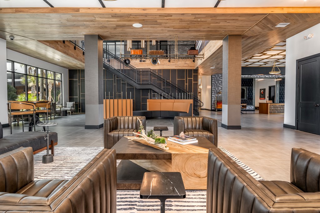 A modern office lobby with brown leather chairs and a wooden table.