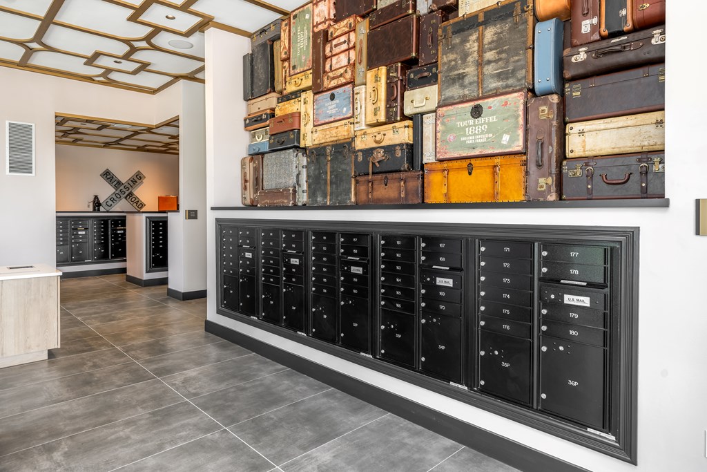 A wall of old suitcases in a room with a row of black lockers.