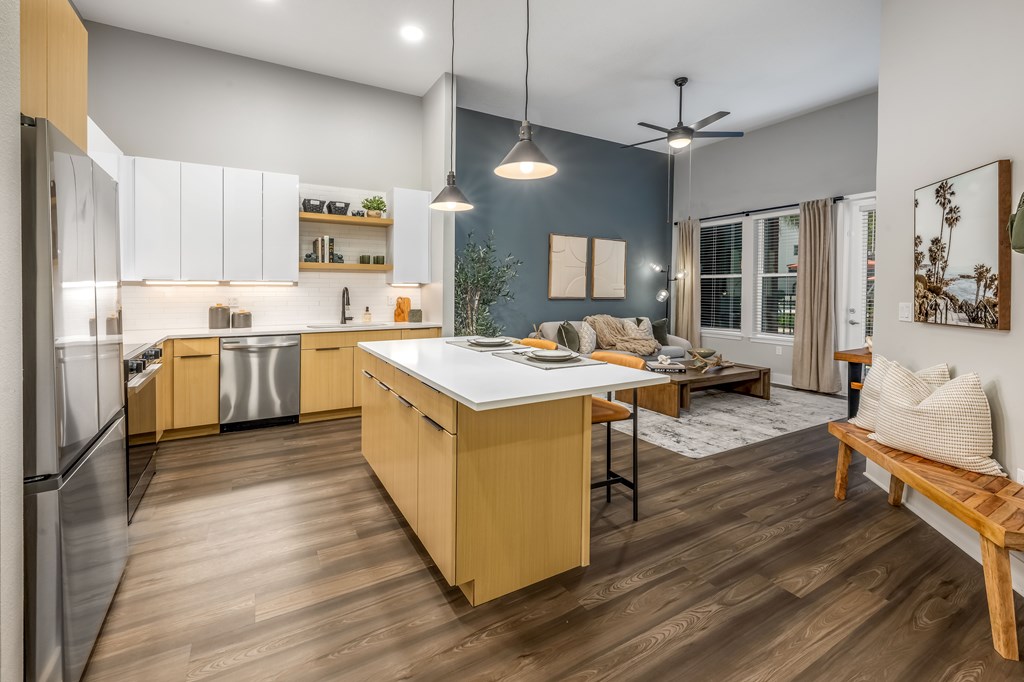 A modern kitchen with wooden floors and stainless steel appliances.