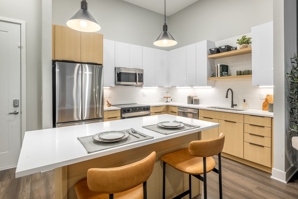 A modern kitchen with a white countertop and wooden cabinets.
