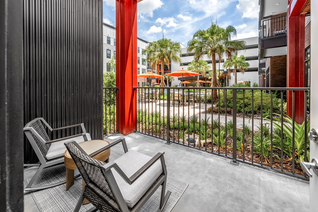 A balcony with a table and chairs overlooking a courtyard.