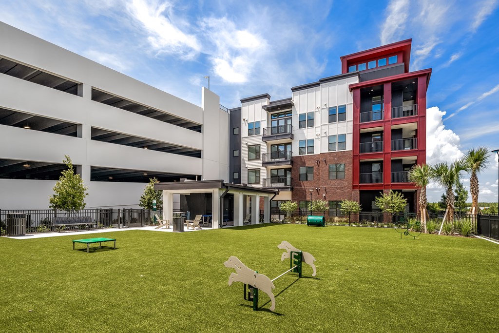 A modern building with a red and white tower and a parking garage in front.