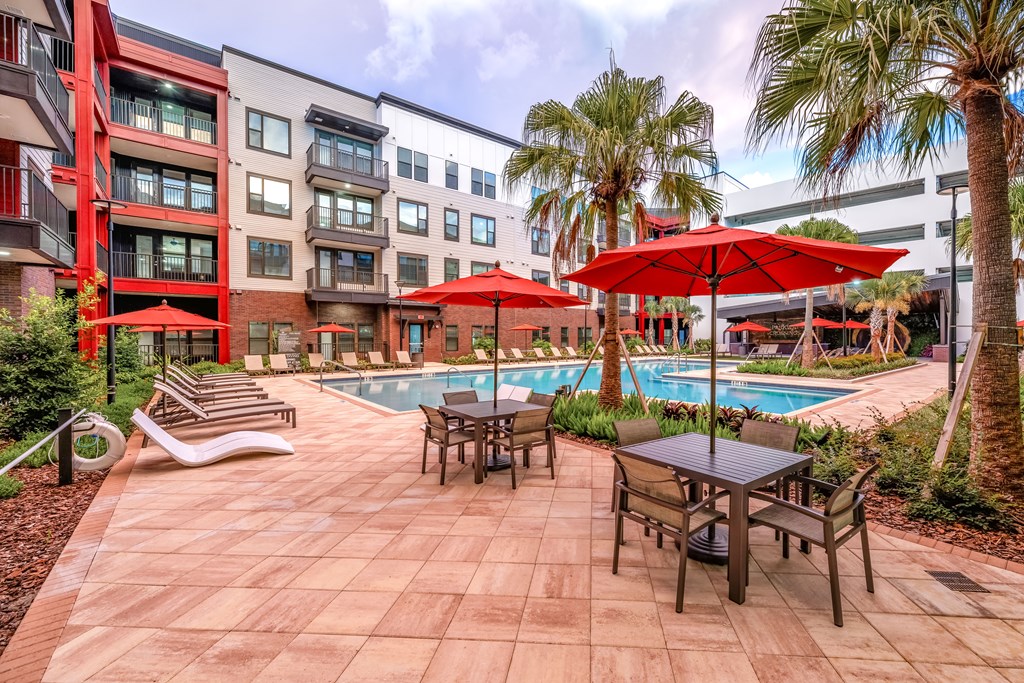 A pool surrounded by chairs and umbrellas in a courtyard.