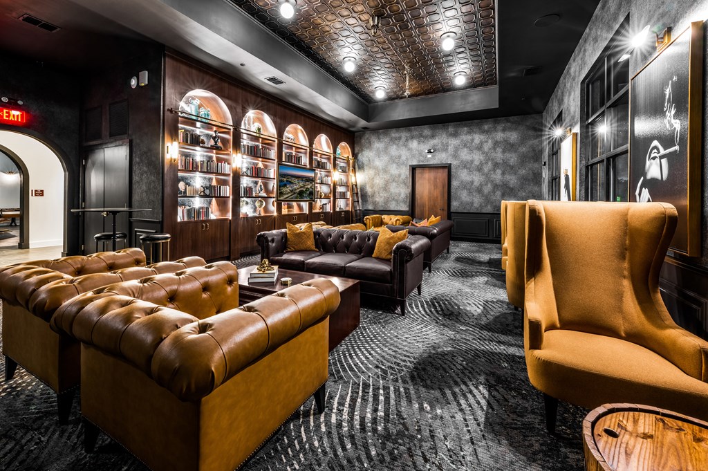 a lounge area with couches and chairs and a wall filled with shelves