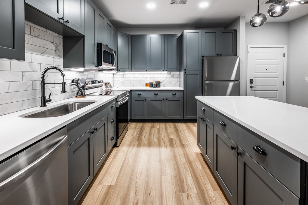 a kitchen with stainless steel appliances and gray cabinets at The Alibi at Lake Lilly, Ocoee, FL