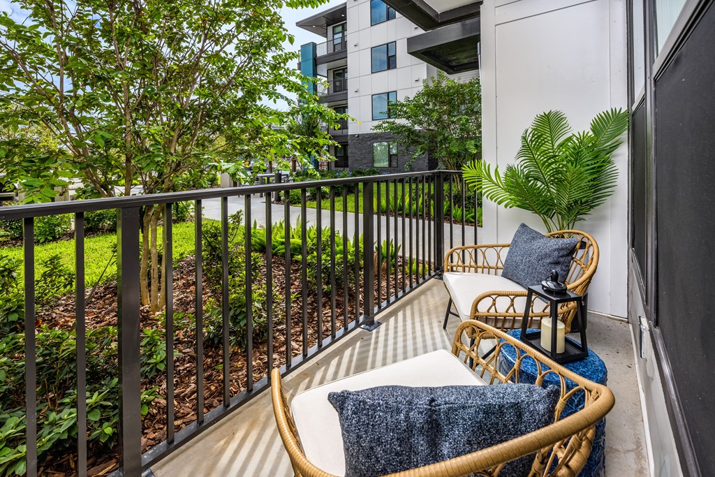 a balcony with two chairs and a table and some plants at The Alibi at Lake Lilly, Ocoee, FL