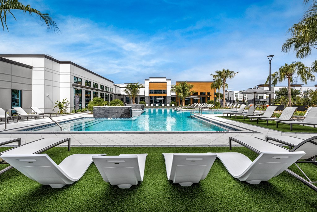 a swimming pool with white chairs and a building in the background at The Alibi at Lake Lilly, Ocoee, FL